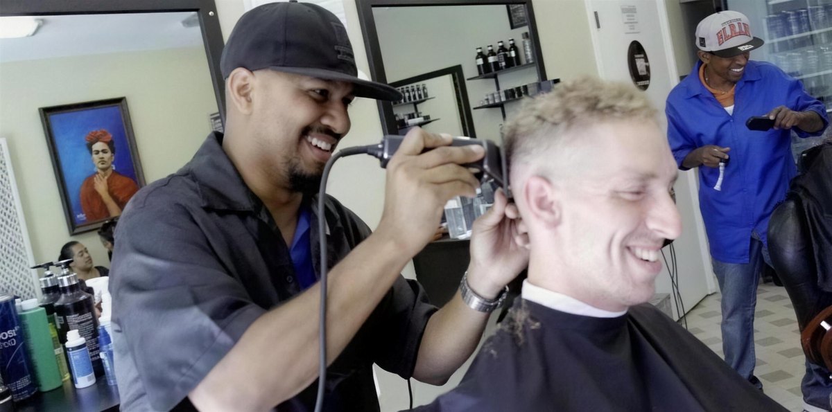 A barber at Champ's running clippers over a customer's fade