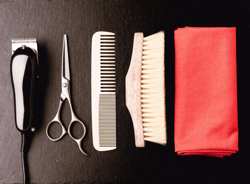A full barber tool kit laid out in a row on slate