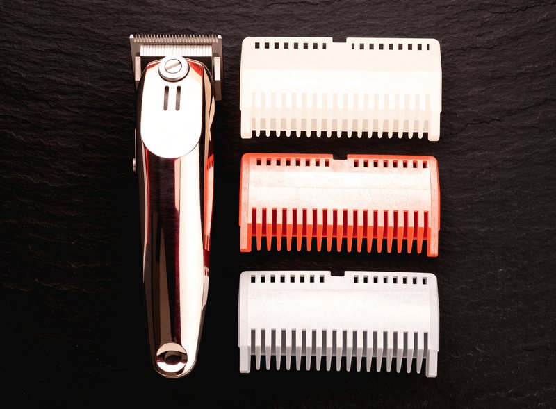 Barber clippers and guard attachments laid out on slate