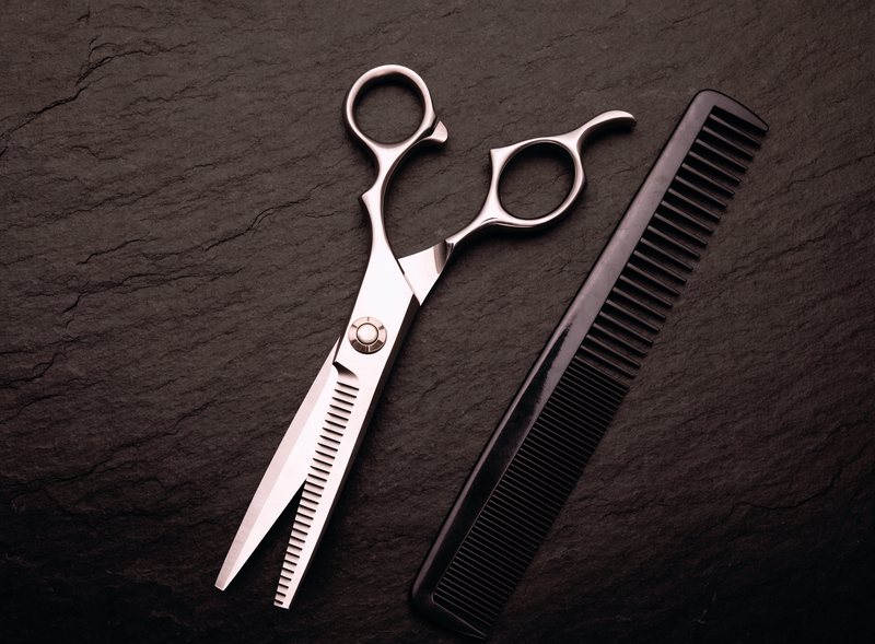 Barber shears and a cutting comb laid out on slate